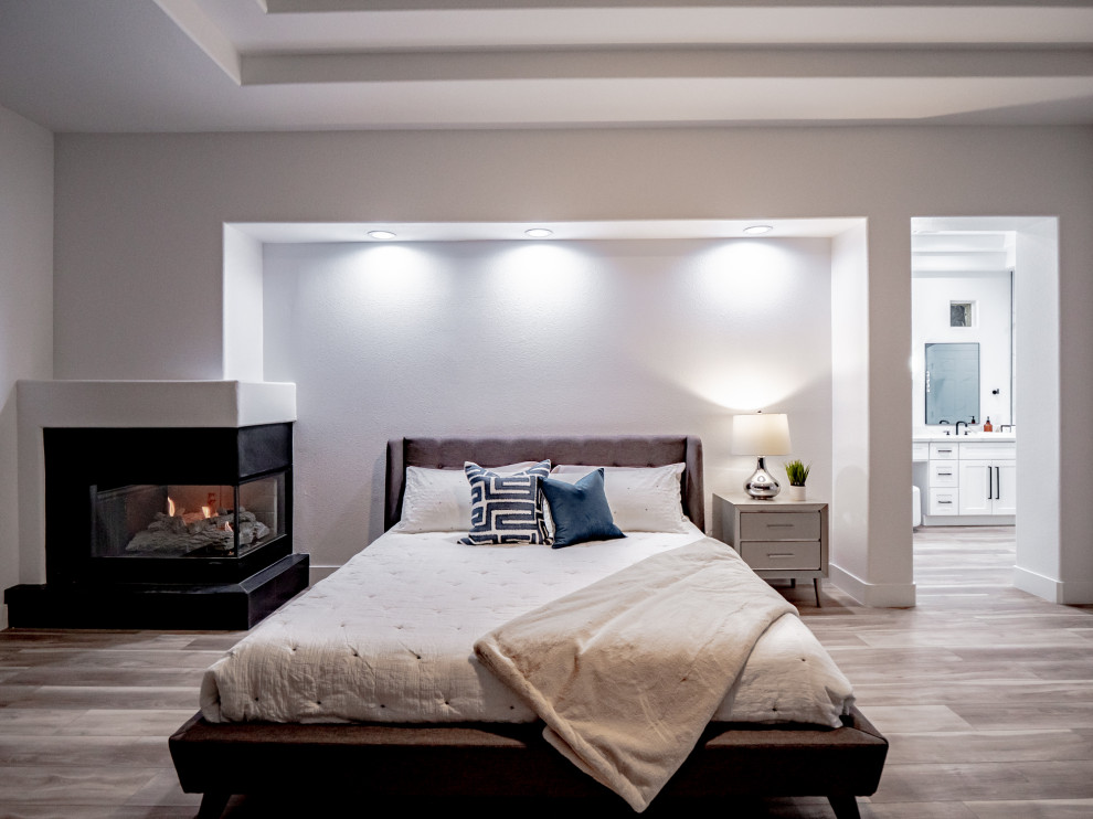 Photo of a contemporary master bedroom in Las Vegas with a corner fireplace, a tile fireplace surround, brown floor, recessed, panelled walls, grey walls and vinyl floors.