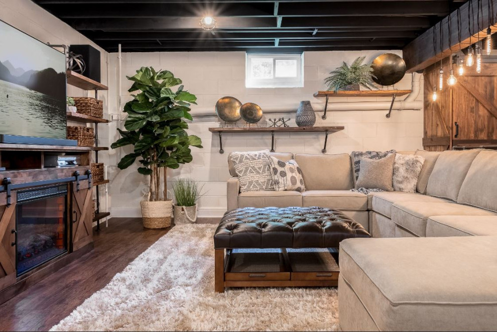 Design ideas for a medium sized industrial look-out basement in Philadelphia with white walls, laminate floors, a standard fireplace, a wooden fireplace surround, brown floors and exposed beams.