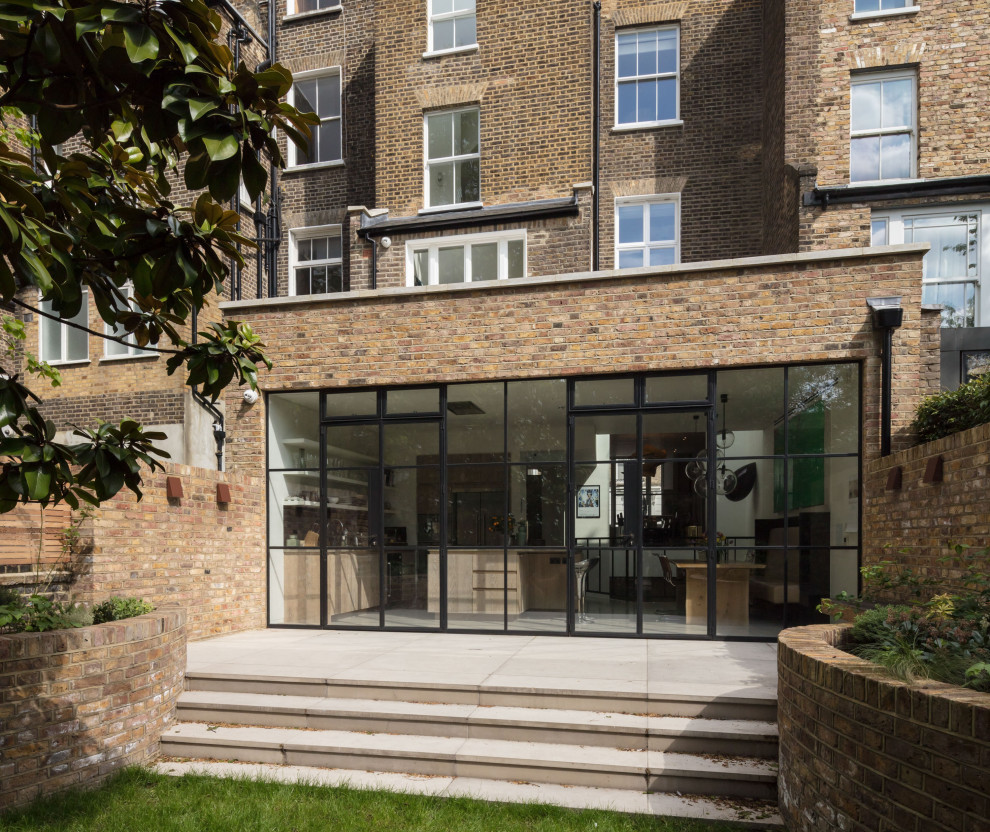 Geometrischer Garten hinter dem Haus mit direkter Sonneneinstrahlung, Natursteinplatten und Steinzaun in London