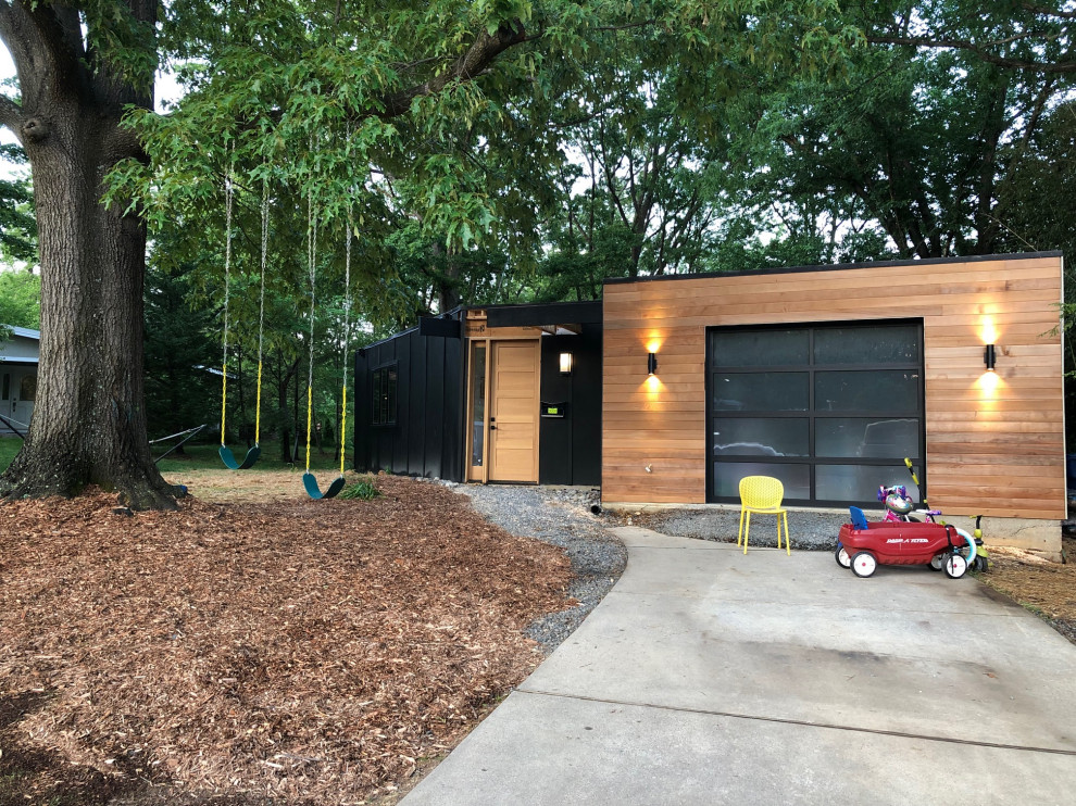 This is an example of a large midcentury one-storey black house exterior in DC Metro with concrete fiberboard siding, a flat roof, a white roof and board and batten siding.