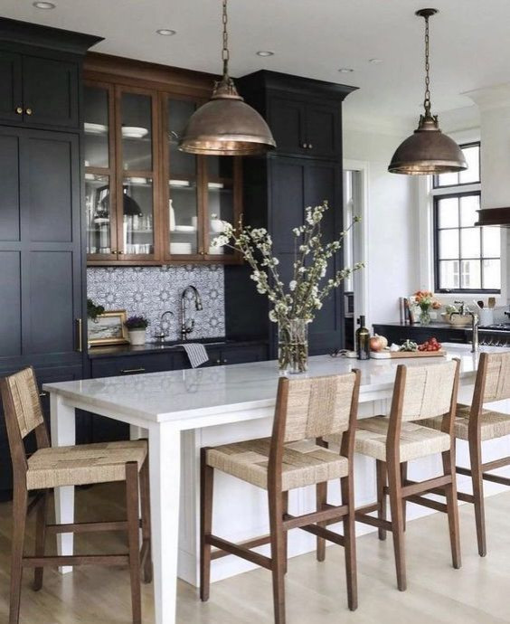 Photo of a large country l-shaped eat-in kitchen in Other with an undermount sink, glass-front cabinets, black cabinets, marble benchtops, black splashback, cement tile splashback, black appliances, light hardwood floors, with island, beige floor and white benchtop.