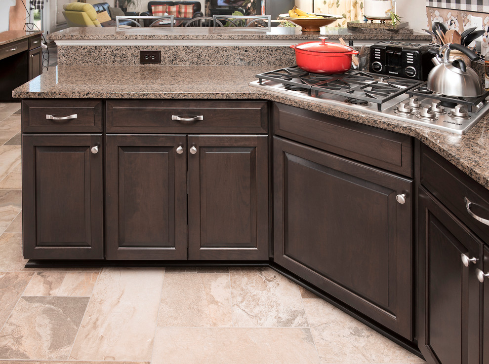 Inspiration for a traditional u-shaped kitchen in Baltimore with a double-bowl sink, raised-panel cabinets, brown cabinets, granite benchtops, black appliances, beige floor and beige benchtop.
