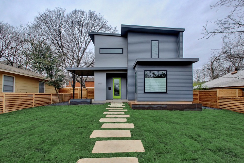 This is an example of a mid-sized midcentury two-storey grey house exterior in Austin with a flat roof, a green roof and wood siding.