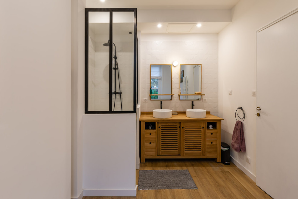 Photo of a large modern master bathroom in Paris with louvered cabinets, medium wood cabinets, a freestanding tub, an open shower, blue tile, ceramic tile, white walls, medium hardwood floors, a vessel sink, wood benchtops, brown floor, an open shower, brown benchtops, a niche, a double vanity and a freestanding vanity.