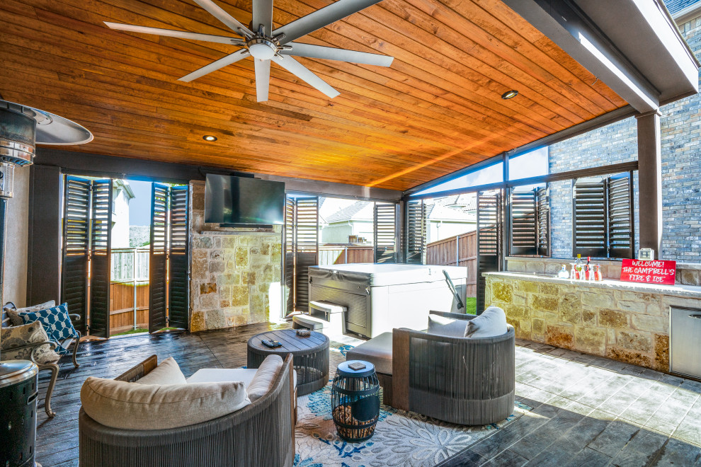 Photo of a large eclectic backyard verandah in Dallas with an outdoor kitchen, stamped concrete and mixed railing.