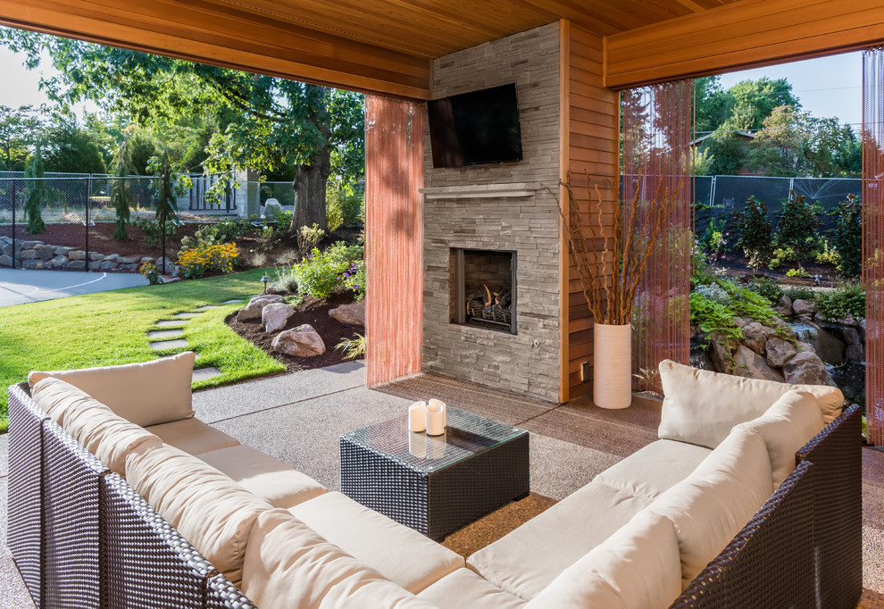 Photo of a contemporary backyard patio in Portland with a fire feature, concrete slab and a roof extension.