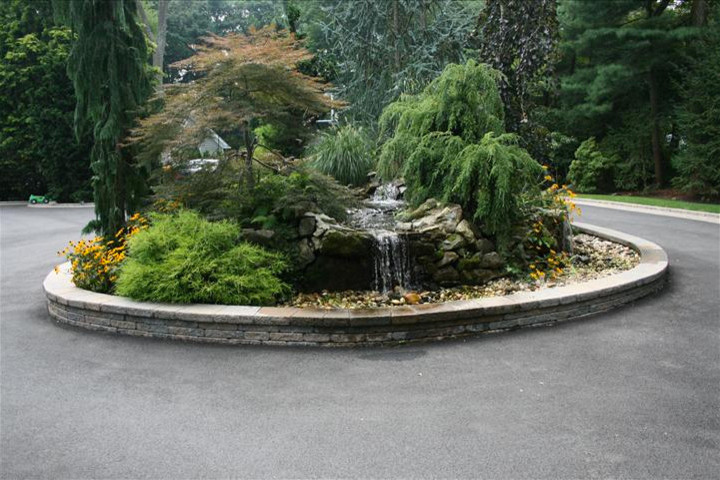 Design ideas for a front yard driveway in New York with with waterfall and concrete pavers.