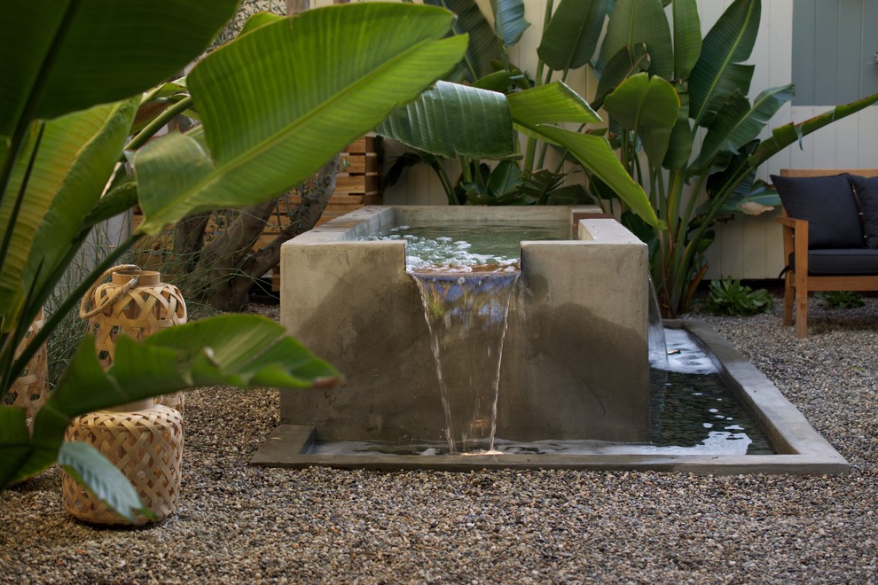 This is an example of a small modern backyard full sun xeriscape in Los Angeles with a water feature and gravel.