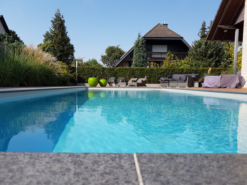 Großer Mediterraner Pool neben dem Haus in rechteckiger Form mit Natursteinplatten in Frankfurt am Main