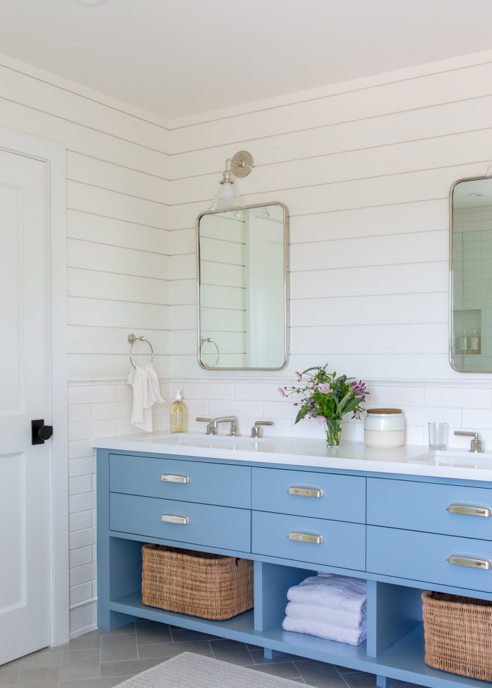 This is an example of a transitional bathroom in San Francisco with flat-panel cabinets, blue cabinets, white tile, subway tile, white walls, an undermount sink, grey floor, white benchtops, a double vanity, a freestanding vanity and planked wall panelling.