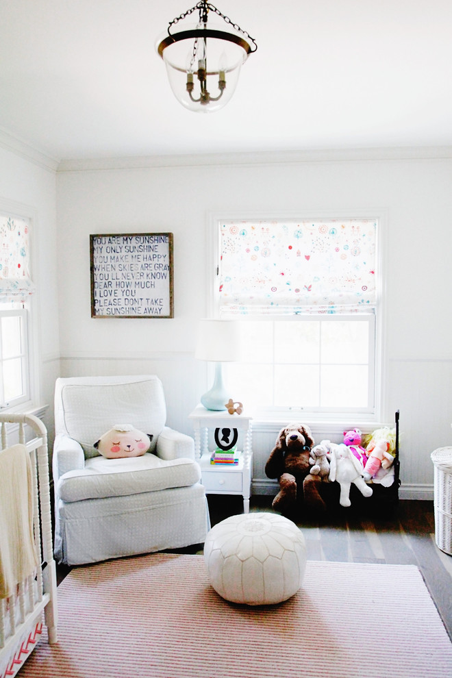 This is an example of a mid-sized transitional nursery for girls in Los Angeles with white walls and light hardwood floors.