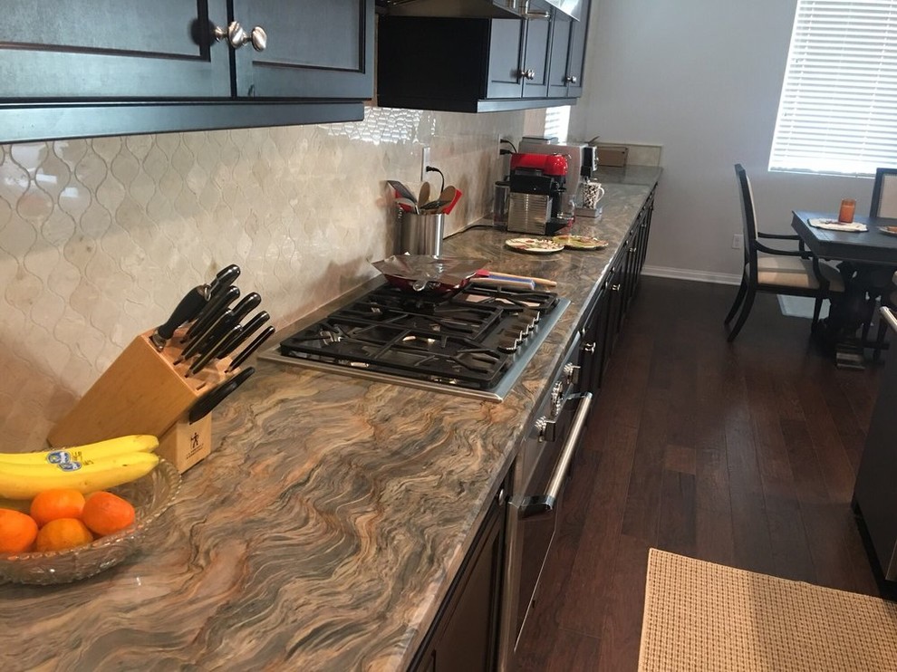 Mid-sized transitional l-shaped painted wood floor and brown floor open concept kitchen photo in Los Angeles with a farmhouse sink, shaker cabinets, brown cabinets, quartz countertops, beige backsplash, porcelain backsplash, stainless steel appliances, an island and beige countertops