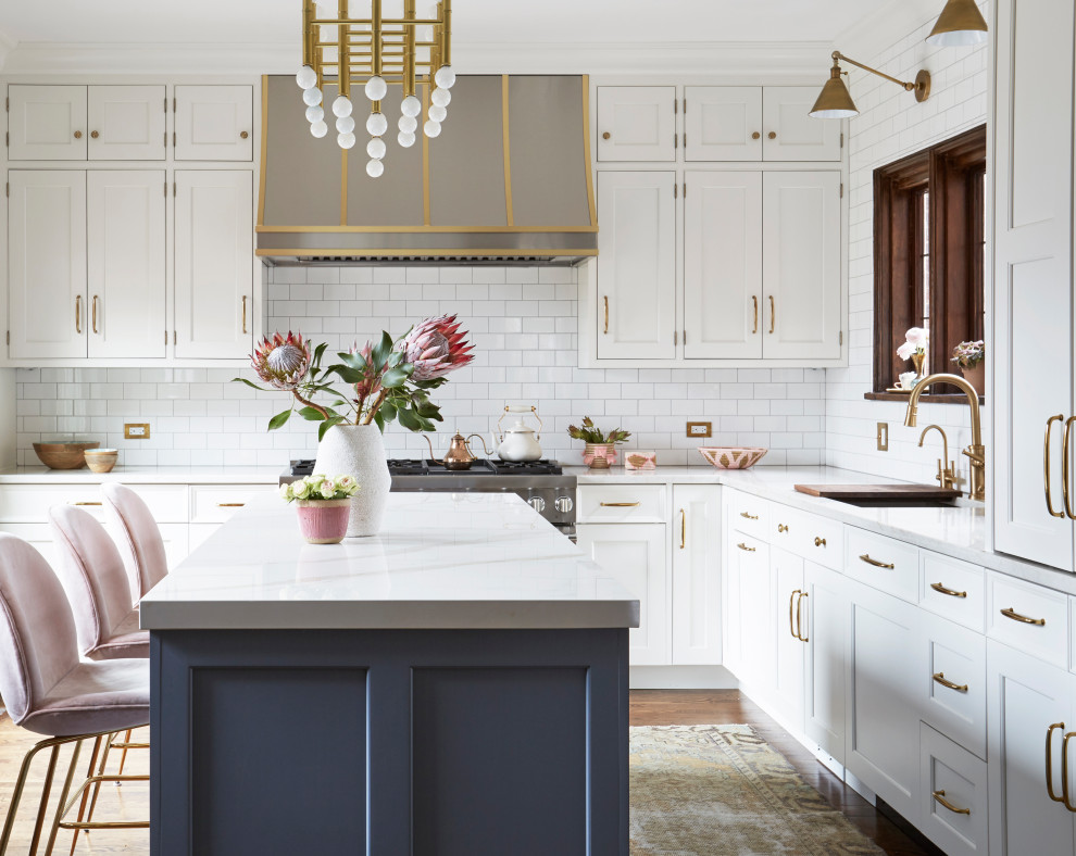 Design ideas for a traditional l-shaped kitchen in Chicago with blue cabinets, white splashback, metro tiled splashback, stainless steel appliances, medium hardwood flooring, an island and white worktops.