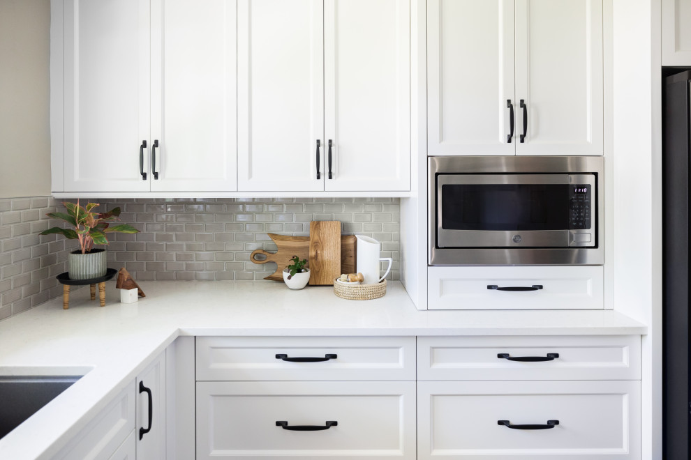 Mid-sized transitional l-shaped medium tone wood floor and brown floor enclosed kitchen photo in Toronto with a double-bowl sink, recessed-panel cabinets, white cabinets, quartz countertops, gray backsplash, porcelain backsplash, stainless steel appliances, an island and gray countertops