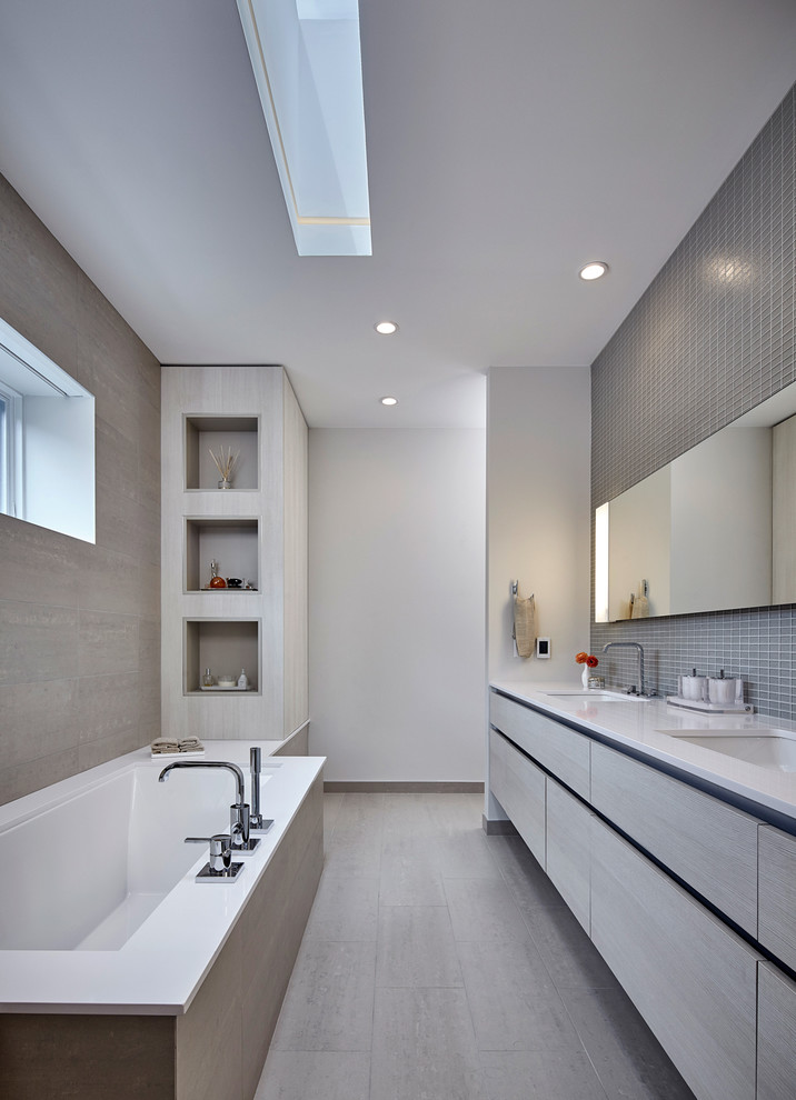 Photo of a large contemporary bathroom in Chicago with flat-panel cabinets, grey cabinets, an undermount tub, gray tile, mosaic tile, white walls and an undermount sink.