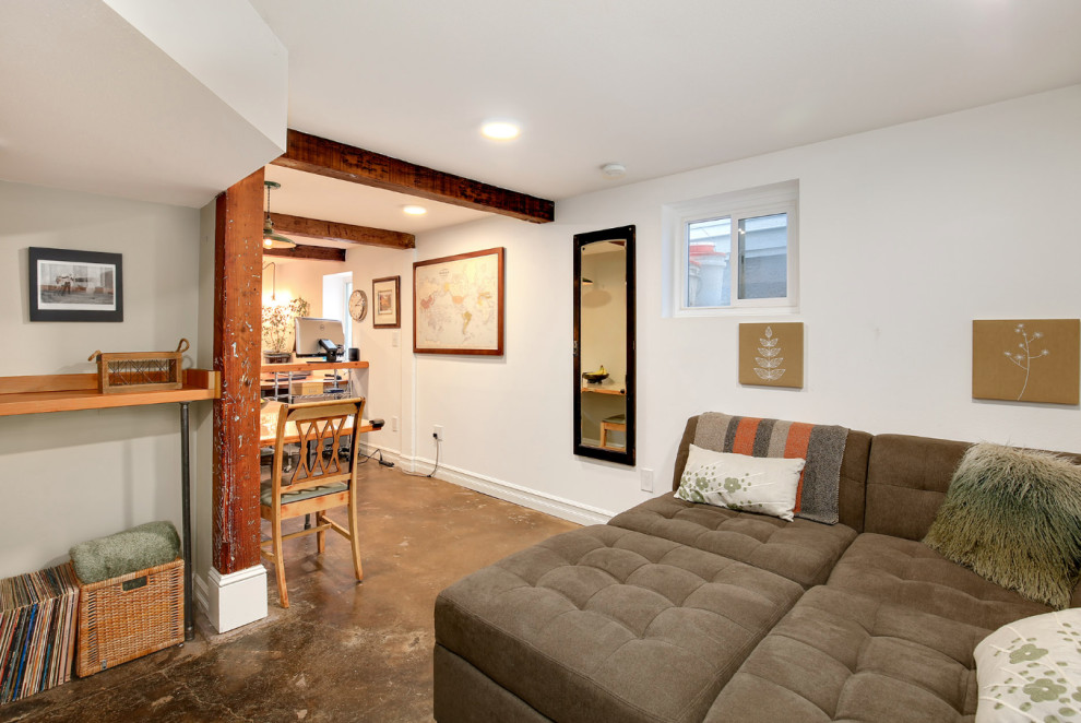 This is an example of a small country basement in Portland with white walls, concrete floors and exposed beam.