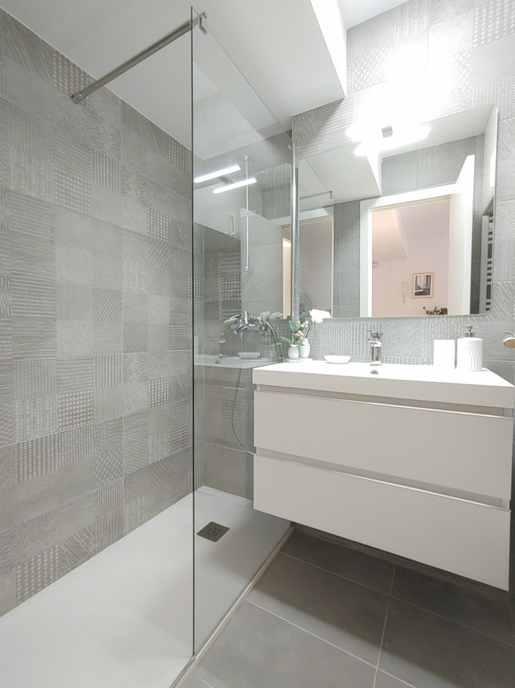 This is an example of a small scandi grey and white ensuite bathroom in Madrid with white cabinets, a built-in shower, grey tiles, ceramic tiles, grey walls, ceramic flooring, a submerged sink, solid surface worktops, grey floors, white worktops, a single sink and a floating vanity unit.