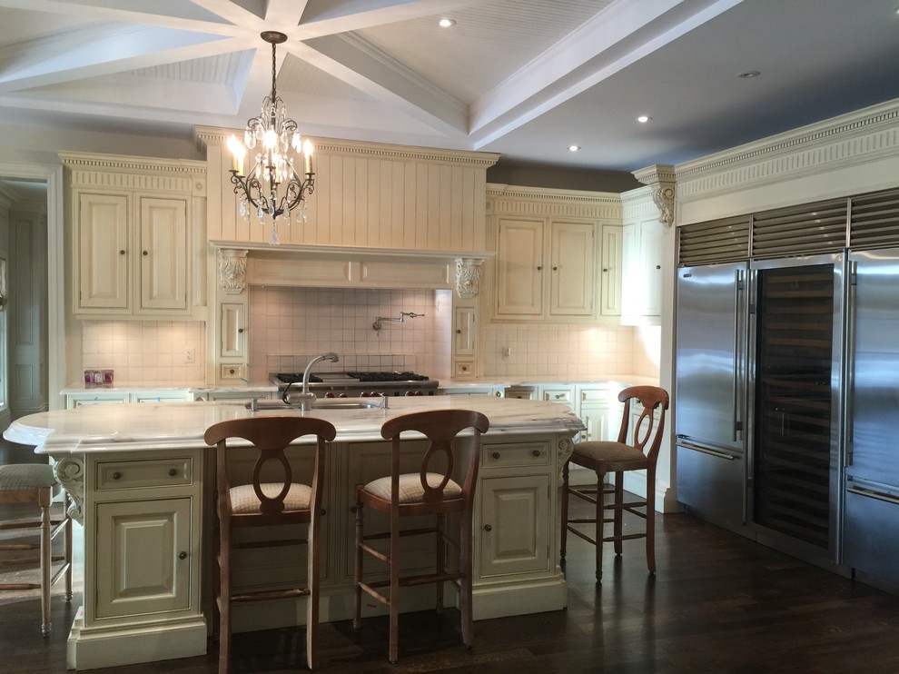 Open concept kitchen - large transitional l-shaped dark wood floor open concept kitchen idea in Toronto with a double-bowl sink, raised-panel cabinets, beige cabinets, stainless steel appliances, an island and white backsplash