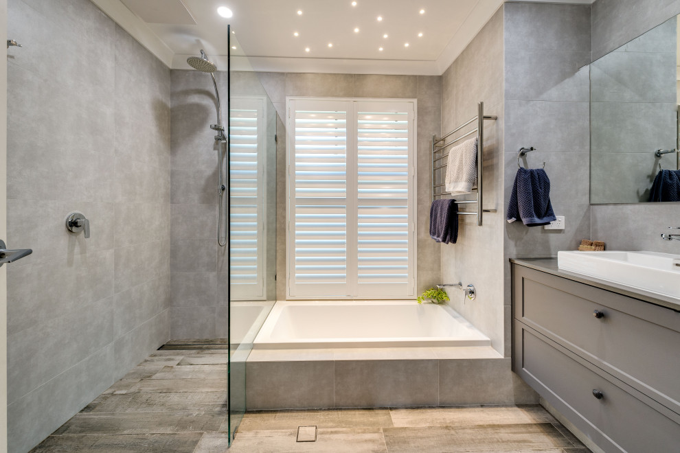 This is an example of a mid-sized contemporary master bathroom in Perth with shaker cabinets, grey cabinets, a drop-in tub, an open shower, gray tile, porcelain tile, grey walls, porcelain floors, a drop-in sink, engineered quartz benchtops, multi-coloured floor and an open shower.