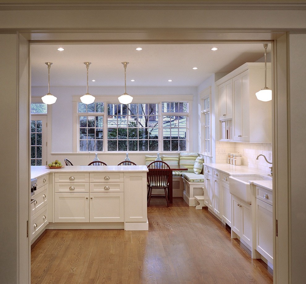 Inspiration for a traditional eat-in kitchen in DC Metro with recessed-panel cabinets, a farmhouse sink, white cabinets, white splashback and subway tile splashback.