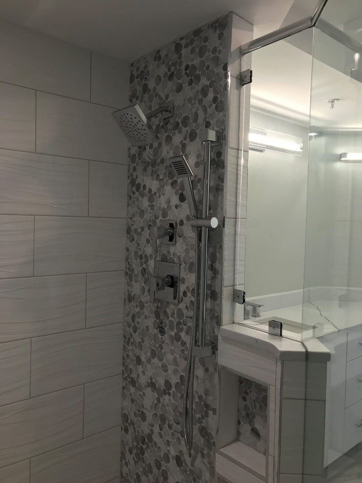 Photo of an expansive contemporary master bathroom in Baltimore with flat-panel cabinets, white cabinets, a freestanding tub, a double shower, a two-piece toilet, white tile, ceramic tile, grey walls, ceramic floors, an undermount sink, engineered quartz benchtops, multi-coloured floor, a hinged shower door and multi-coloured benchtops.