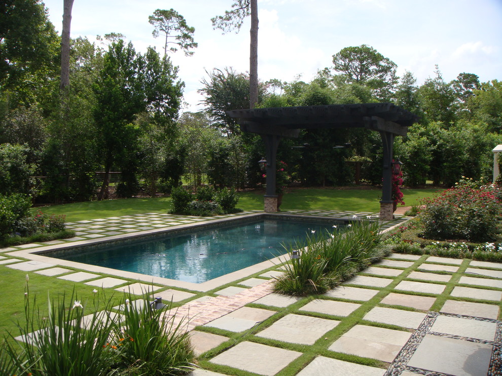 Inspiration for a large traditional backyard rectangular lap pool in Houston with a water feature and concrete pavers.