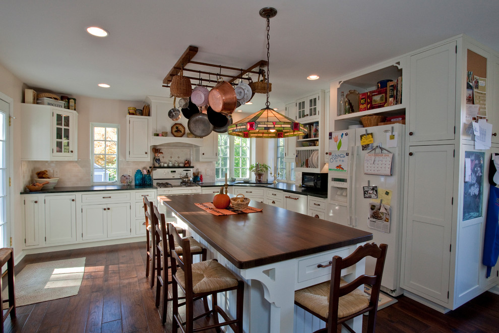 Photo of a mid-sized traditional l-shaped eat-in kitchen in Philadelphia with an undermount sink, shaker cabinets, white cabinets, wood benchtops, beige splashback, white appliances, dark hardwood floors and with island.