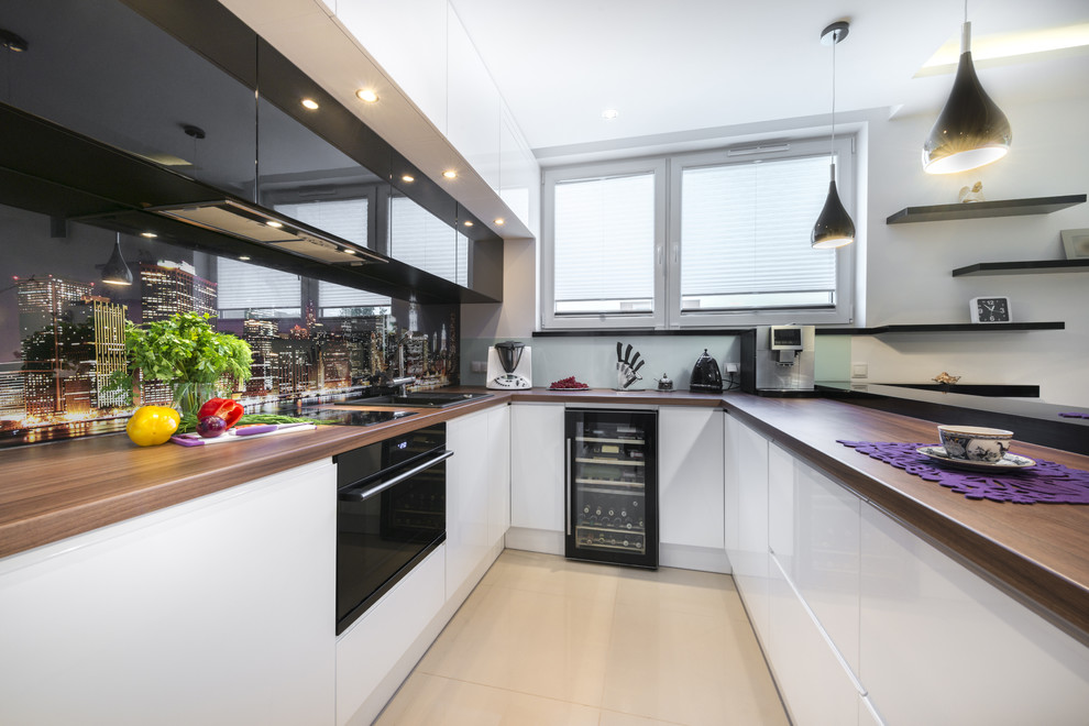 Inspiration for a mid-sized modern u-shaped eat-in kitchen in New York with a double-bowl sink, flat-panel cabinets, white cabinets, wood benchtops, multi-coloured splashback, black appliances, porcelain floors, a peninsula and beige floor.