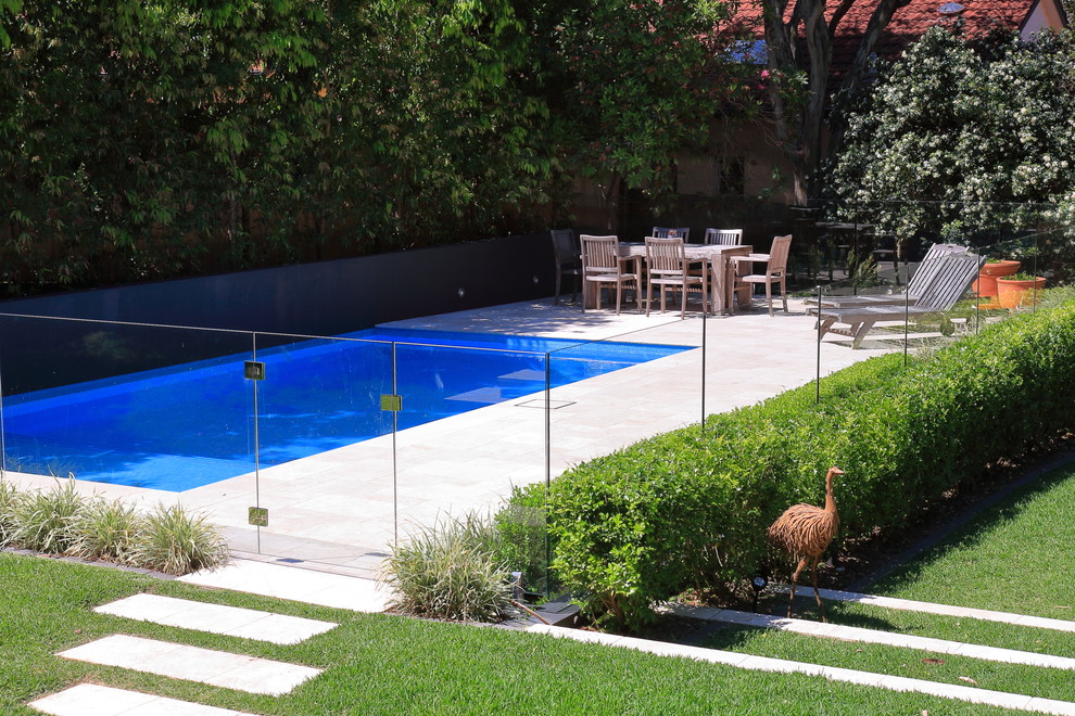 Photo of a mid-sized contemporary backyard rectangular pool in Sydney with natural stone pavers.