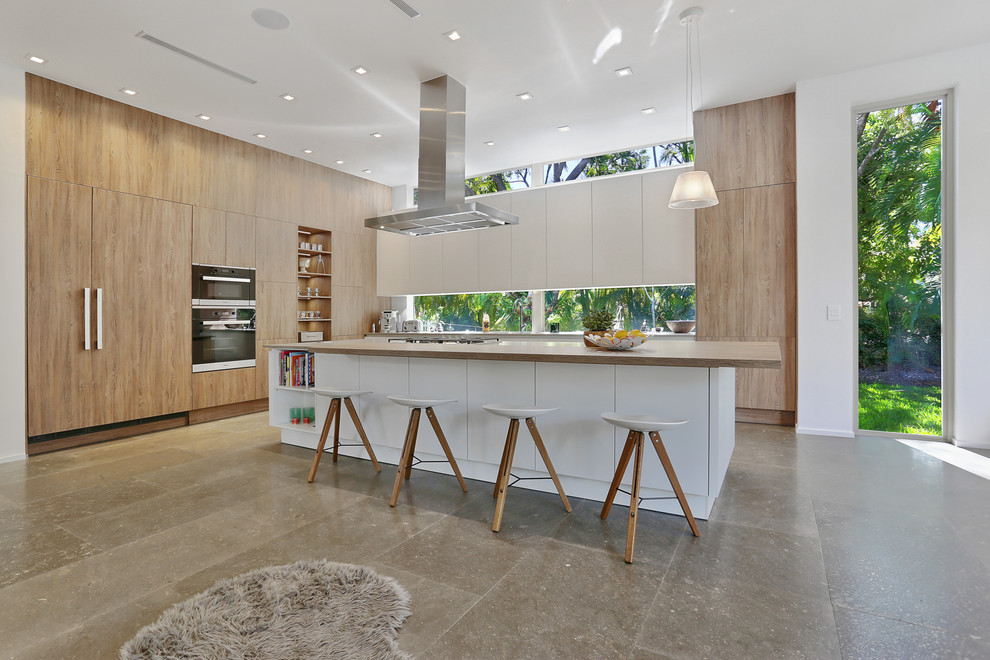 Design ideas for a large contemporary galley open plan kitchen in Miami with an undermount sink, flat-panel cabinets, white cabinets, concrete benchtops, window splashback, panelled appliances, concrete floors and with island.