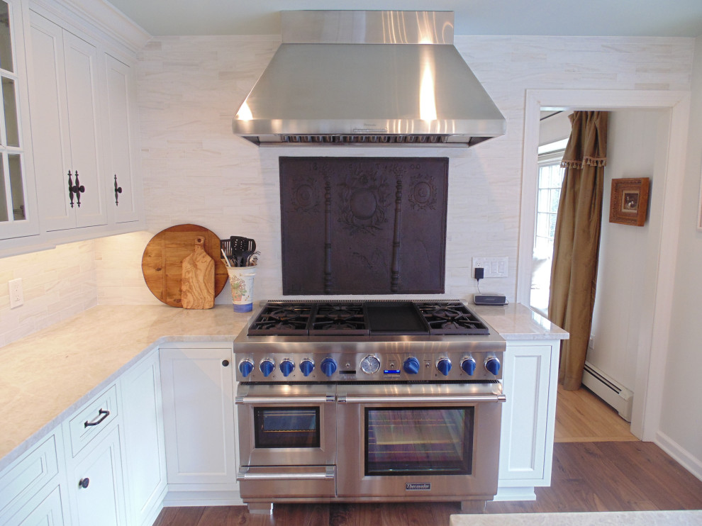 Large transitional u-shaped medium tone wood floor and brown floor eat-in kitchen photo with an undermount sink, recessed-panel cabinets, white cabinets, quartzite countertops, beige backsplash, subway tile backsplash, stainless steel appliances, an island and beige countertops
