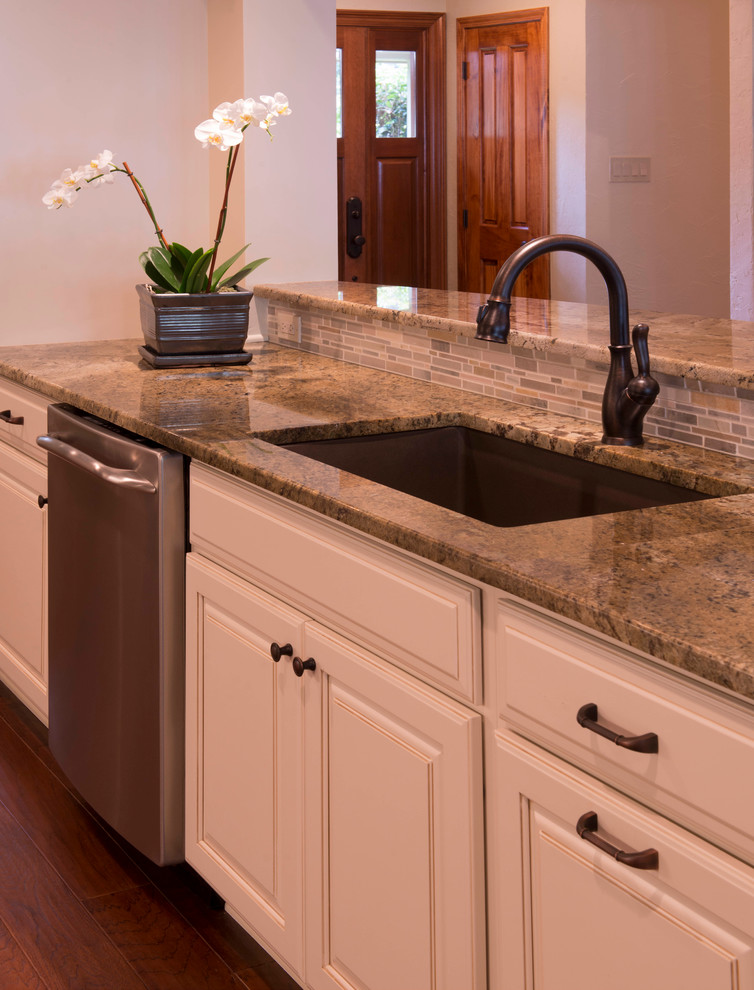 Example of a transitional galley open concept kitchen design in New Orleans with an undermount sink, raised-panel cabinets, white cabinets, granite countertops, gray backsplash, mosaic tile backsplash and stainless steel appliances