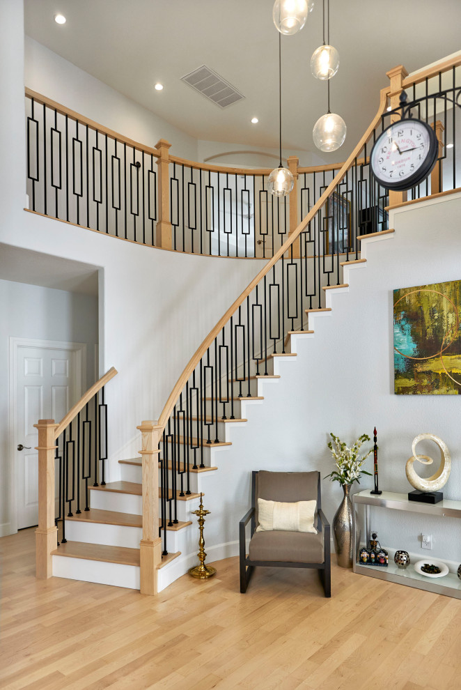 Источник вдохновения для домашнего уюта: огромная изогнутая лестница в стиле неоклассика (современная классика) с деревянными ступенями, крашенными деревянными подступенками и металлическими перилами