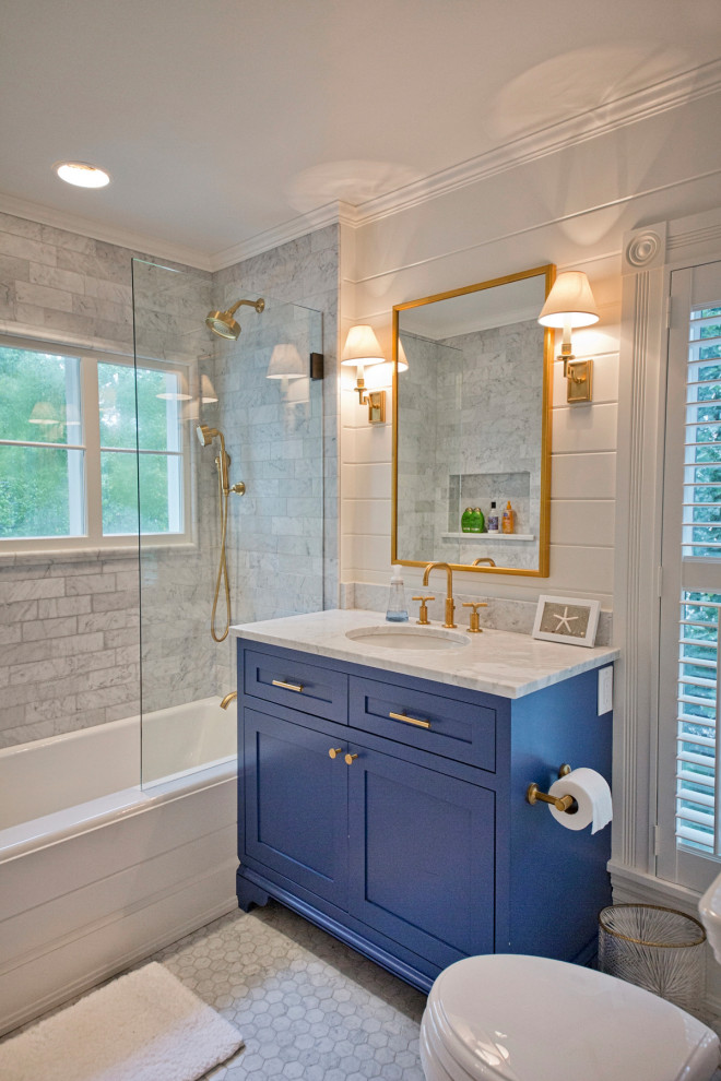 Design ideas for a mid-sized transitional 3/4 bathroom in Cleveland with shaker cabinets, blue cabinets, an alcove tub, a shower/bathtub combo, a two-piece toilet, gray tile, white tile, porcelain tile, porcelain floors, an undermount sink, grey floor and grey benchtops.