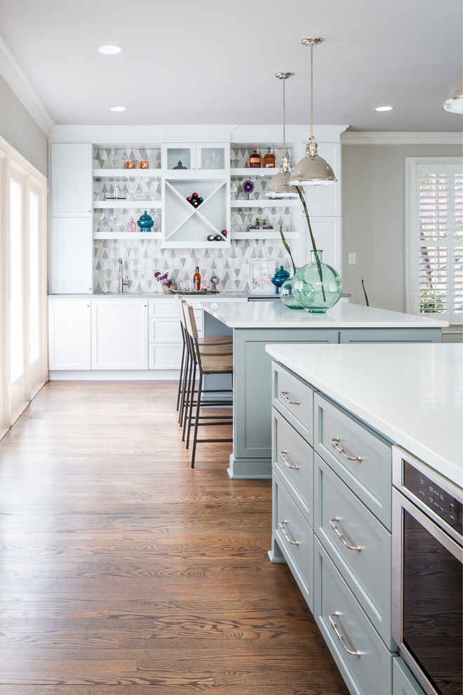 Example of a huge transitional galley medium tone wood floor open concept kitchen design in Raleigh with a farmhouse sink, flat-panel cabinets, white cabinets, quartz countertops, gray backsplash, ceramic backsplash, stainless steel appliances and two islands