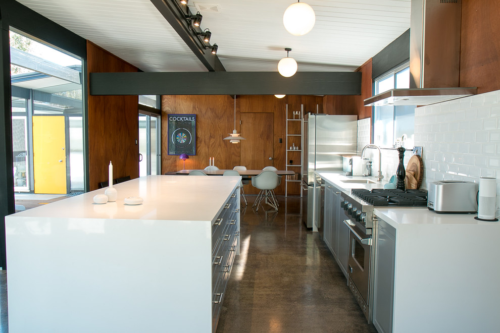 Inspiration for a mid-sized midcentury single-wall eat-in kitchen in San Francisco with an integrated sink, recessed-panel cabinets, grey cabinets, quartzite benchtops, white splashback, ceramic splashback, stainless steel appliances, concrete floors and with island.