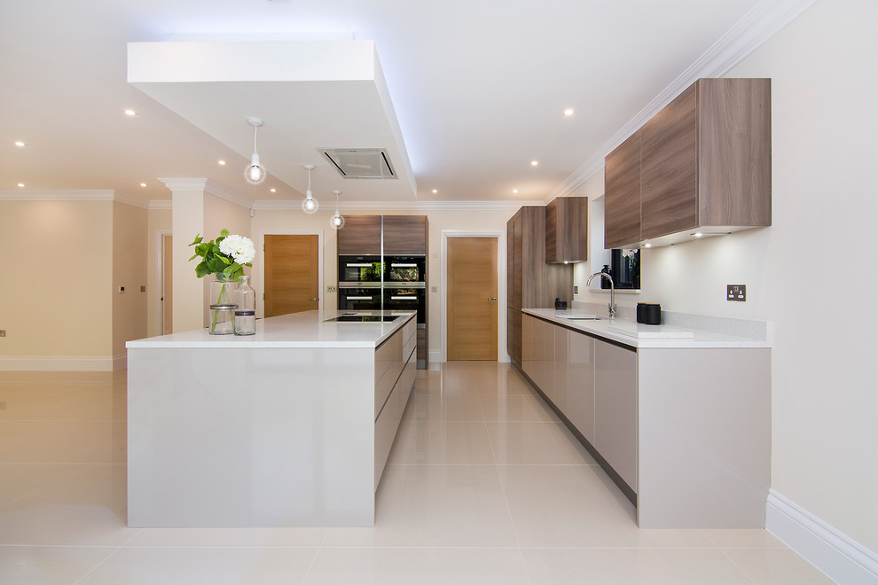 Medium sized modern open plan kitchen in Essex with a double-bowl sink, flat-panel cabinets, medium wood cabinets, quartz worktops, white splashback, stone slab splashback, black appliances, porcelain flooring, an island, white floors and white worktops.