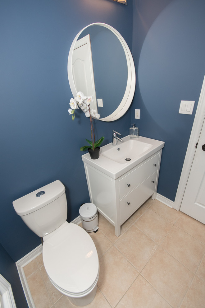 Design ideas for a mid-sized contemporary powder room in Toronto with shaker cabinets, white cabinets, a two-piece toilet, blue walls, porcelain floors, an integrated sink and beige floor.