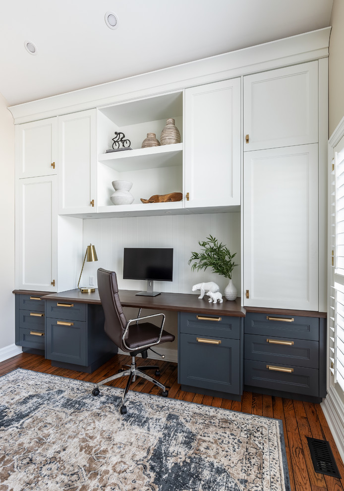 Photo of a mid-sized transitional study room in Toronto with medium hardwood floors, a built-in desk, white walls, no fireplace and brown floor.