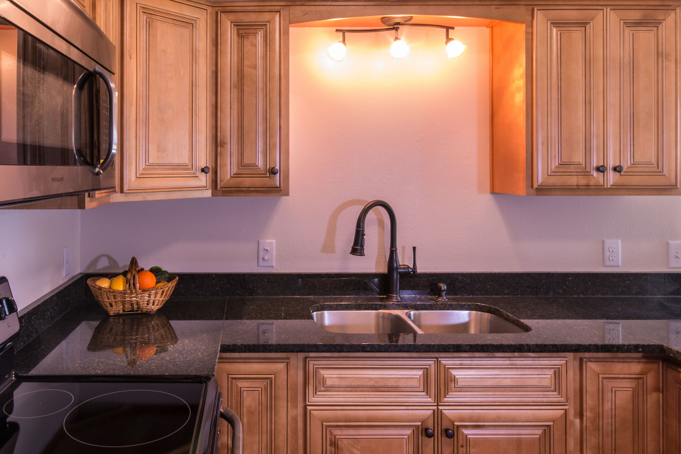 Small u-shaped eat-in kitchen photo with an undermount sink, raised-panel cabinets, medium tone wood cabinets, granite countertops, stainless steel appliances and a peninsula