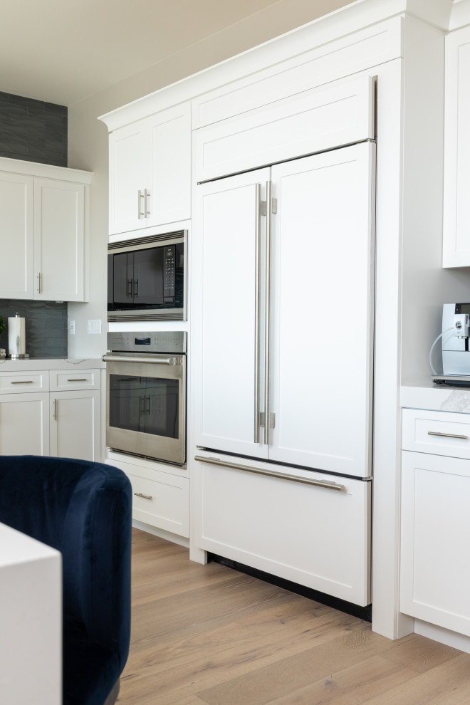 Mid-sized transitional l-shaped eat-in kitchen photo in Orange County with shaker cabinets, white cabinets, quartz countertops, gray backsplash, subway tile backsplash, stainless steel appliances, an island and white countertops