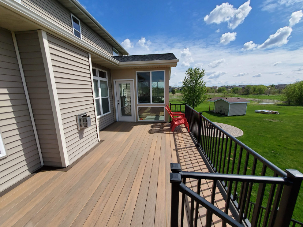 Example of a large backyard second story metal railing deck design with a roof extension
