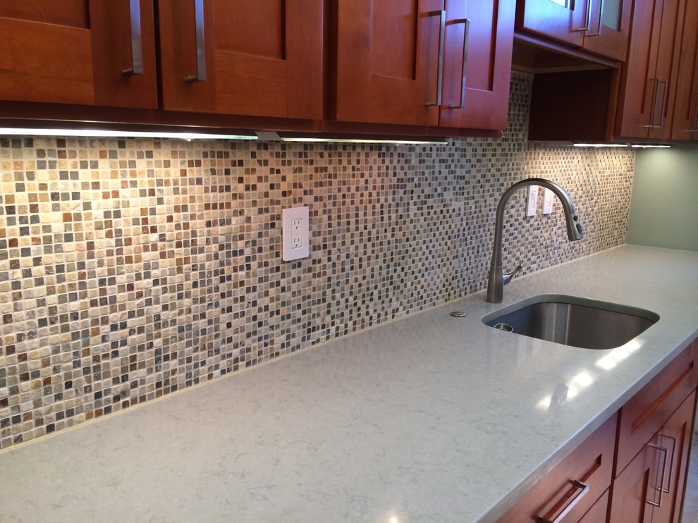 Inspiration for a mid-sized transitional u-shaped limestone floor and beige floor enclosed kitchen remodel in DC Metro with an undermount sink, shaker cabinets, medium tone wood cabinets, beige backsplash, mosaic tile backsplash, stainless steel appliances, quartz countertops and an island