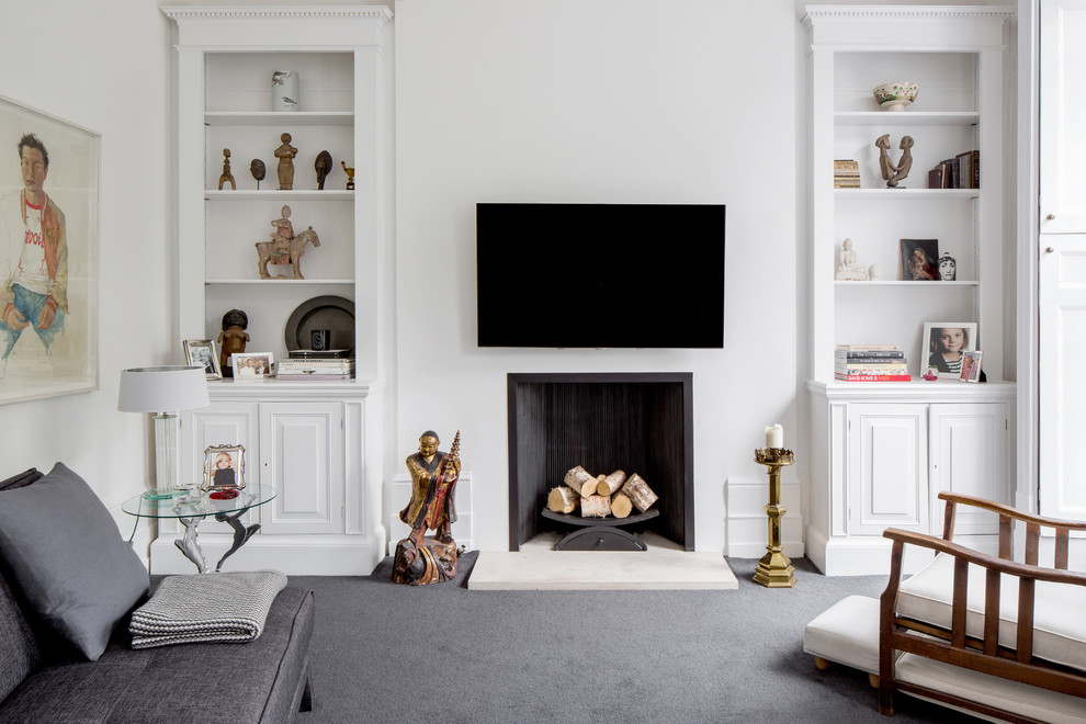Design ideas for a mid-sized transitional enclosed living room in London with white walls, carpet, a standard fireplace, a wall-mounted tv and grey floor.