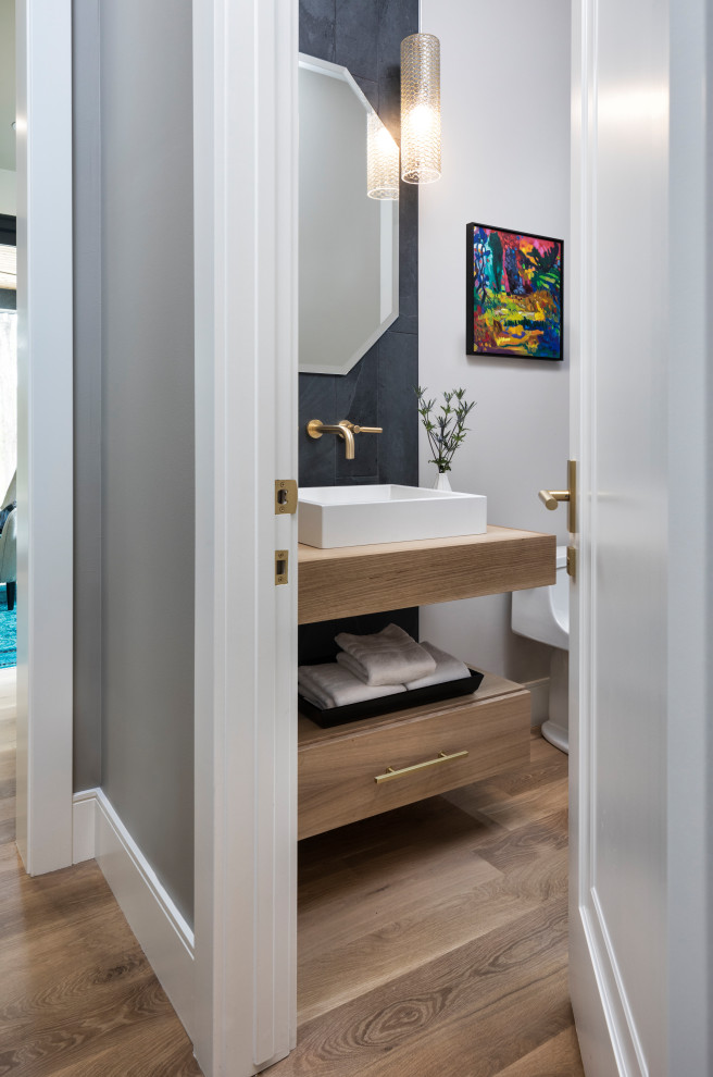 Mid-sized contemporary bathroom in Minneapolis with flat-panel cabinets, brown cabinets, a one-piece toilet, white tile, porcelain tile, white walls, light hardwood floors, a vessel sink, wood benchtops, brown floor and brown benchtops.