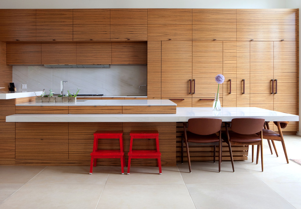 This is an example of an expansive contemporary kitchen in New York with an undermount sink, flat-panel cabinets, medium wood cabinets, white splashback, marble splashback, panelled appliances, with island and beige floor.
