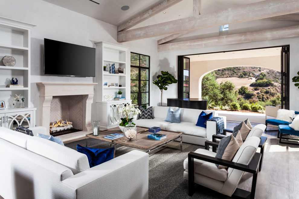 Example of a transitional open concept medium tone wood floor, brown floor, exposed beam and vaulted ceiling living room design in Orange County with a music area, white walls, a wall-mounted tv and a standard fireplace