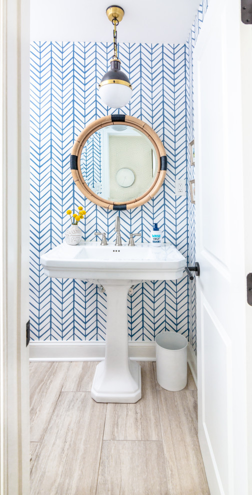 Inspiration for a small beach style bathroom in Baltimore with white cabinets, a two-piece toilet, blue walls, ceramic floors, a pedestal sink, solid surface benchtops, grey floor, white benchtops, a single vanity, a freestanding vanity, wallpaper and wallpaper.