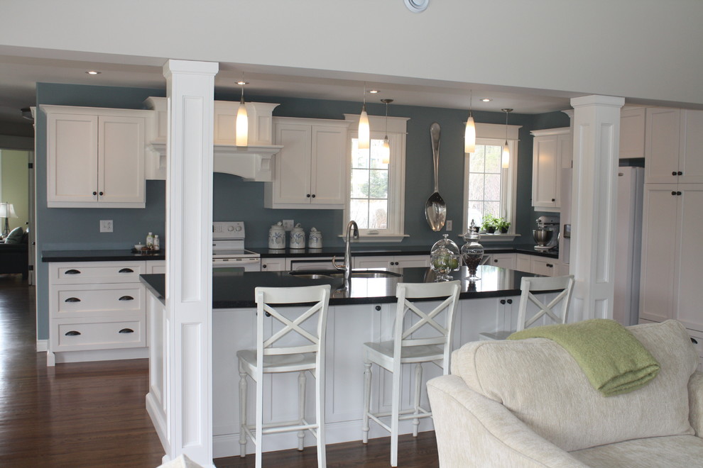 Photo of a mid-sized transitional l-shaped kitchen in Other with an undermount sink, shaker cabinets, white cabinets, soapstone benchtops, blue splashback, white appliances, medium hardwood floors and with island.
