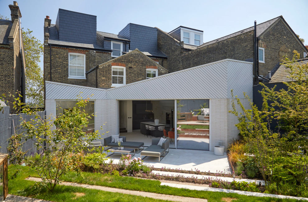 Photo of an expansive contemporary patio in London with natural stone pavers and no cover.